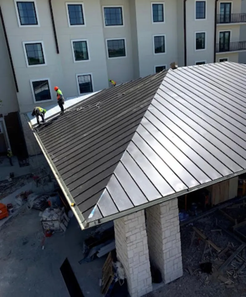 Crew installing standing seam metal roof panels on a commercial project in Palmer Town